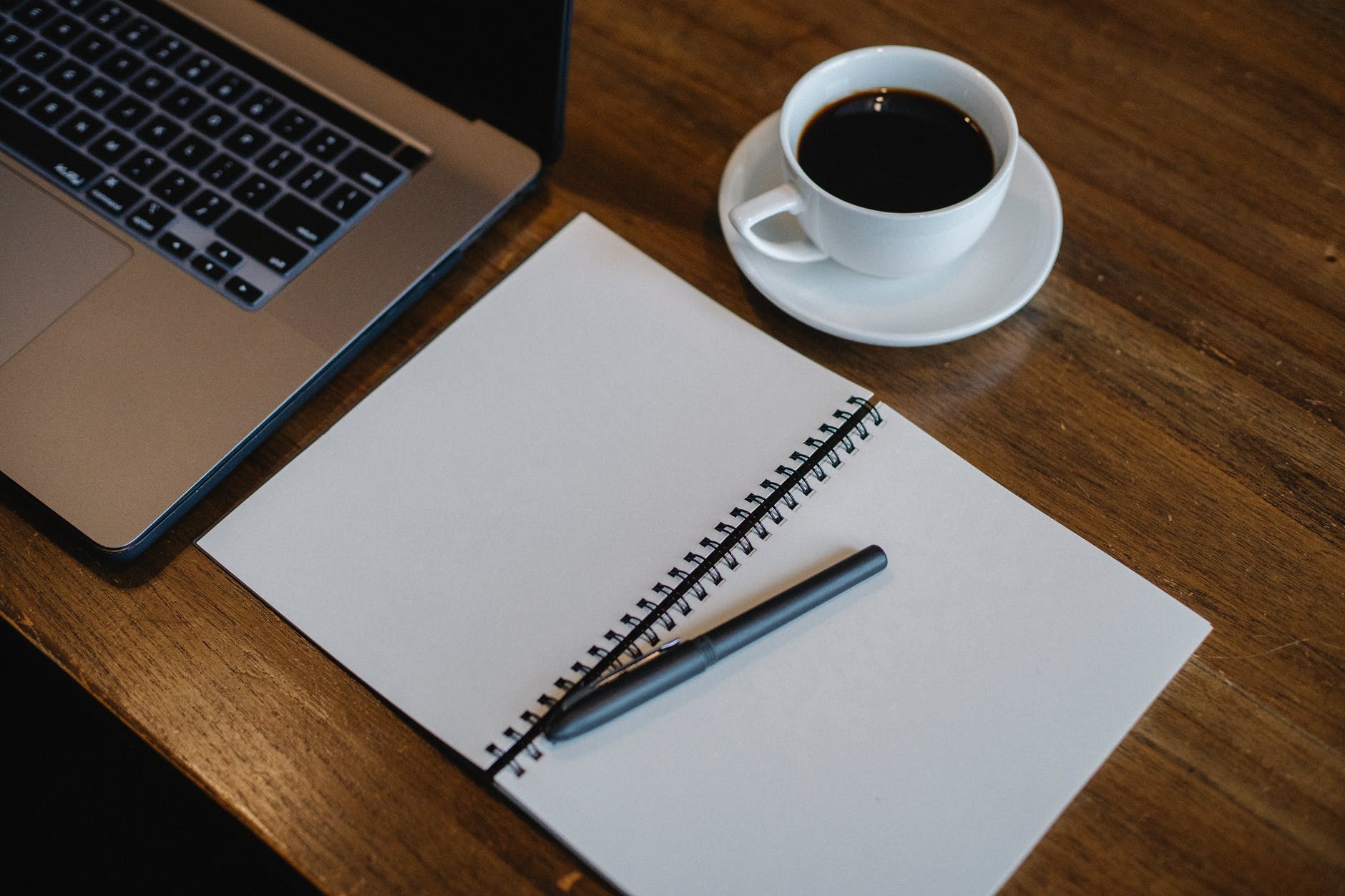 laptop and notepad near cup of coffee