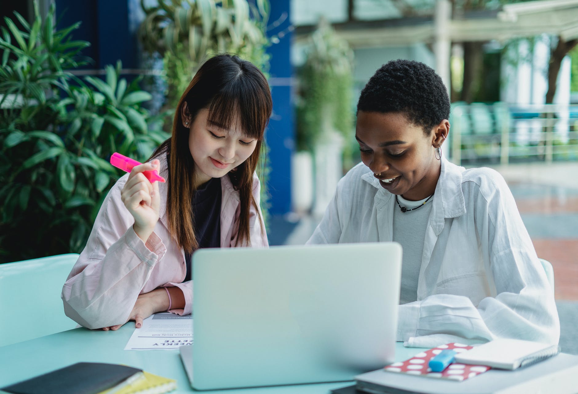 smiling diverse girlfriends with laptop studying outdoors